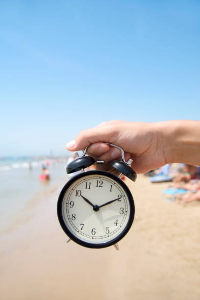 istock young man with an alarm clock on the beach 830771688