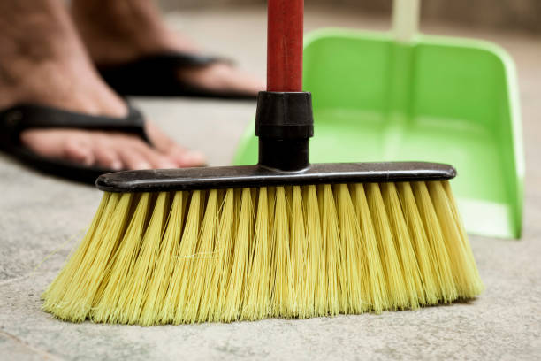 istock young man sweeping the floor with a broom 830771870