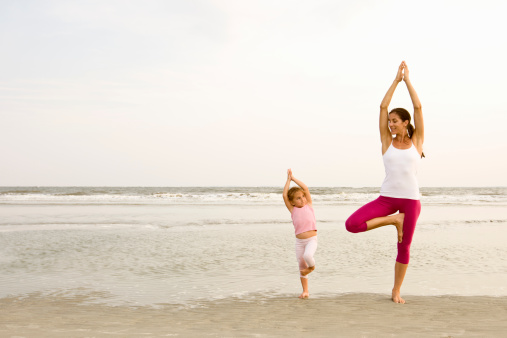 Woman enjoying peaceful yoga exercise on beach with daughter. Carolina.  Evening light.  