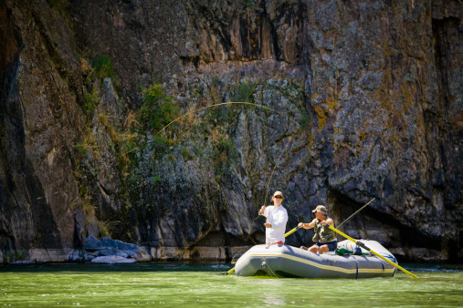 Two men (mid-30s and mid-50s) rafting and fly fishing on the Gunnison Gorge on the South Fork of the Gunnison River, Montrose, Colorado. This section of river goes through dramatic rock canyons and is one of the most scenic rivers in Colorado.