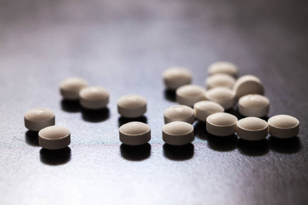 backlit white pills - opioid and prescription medication addiction epidemic or crisis - concept - hydrocodone imagens e fotografias de stock