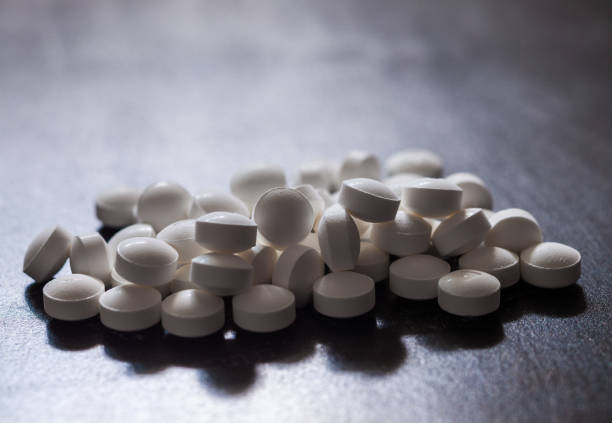backlit white pills - opioid and prescription medication addiction epidemic or crisis - concept - hydrocodone imagens e fotografias de stock