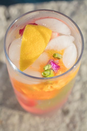 Glass of cold water infused with fruit, mint and edible flowers and ice