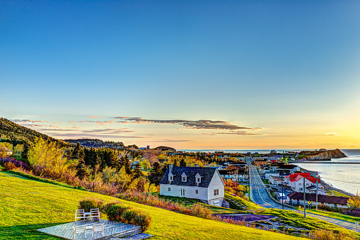 Hotel chairs on hill during sunrise in Perce, Gaspe Peninsula, Quebec, Canada, Gaspesie region with cityscape