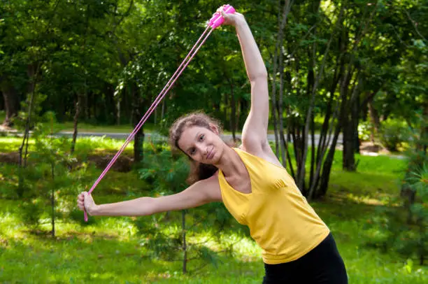 Girl is engaged fitness in park, exercise with skipping rope