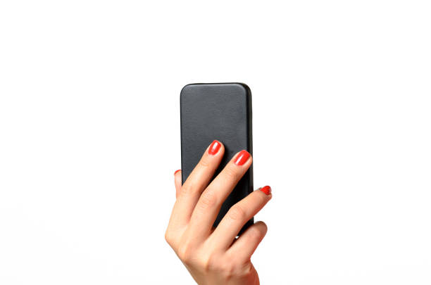 Young woman with red painted fingernails holding a mobile phone in the air with the back towards the camera, close up isolated on white