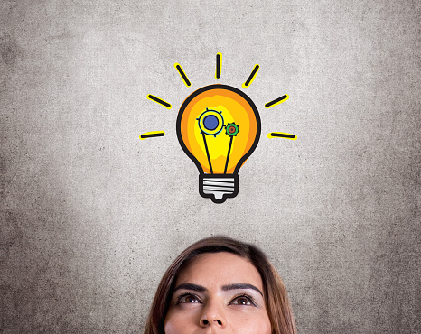 Headshot of successful businesswoman with light bulb icon on wall