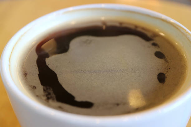 istock Close up of hot black coffee in a white cup with thin layer of form, selective focus 831032318