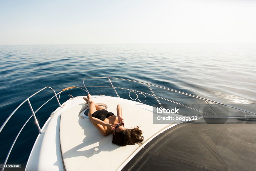Poses de mujer joven atractiva en yate de lujo flotando en el mar - Foto de stock de Yate libre de derechos