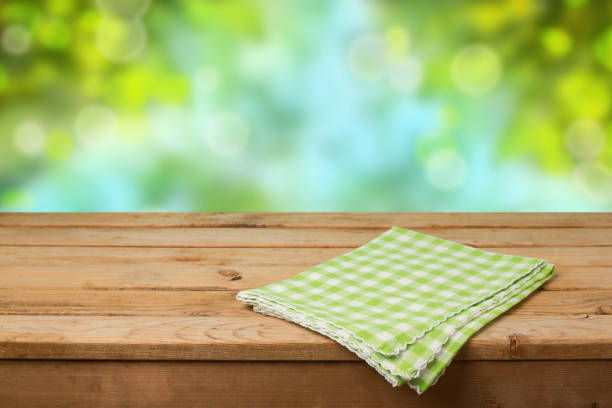 istock Empty wooden deck table with checked tablecloth over green nature bokeh background for product montage display 831046582