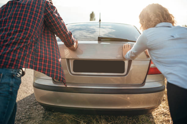 istock Man and woman pushing a broken car, back view 831048722