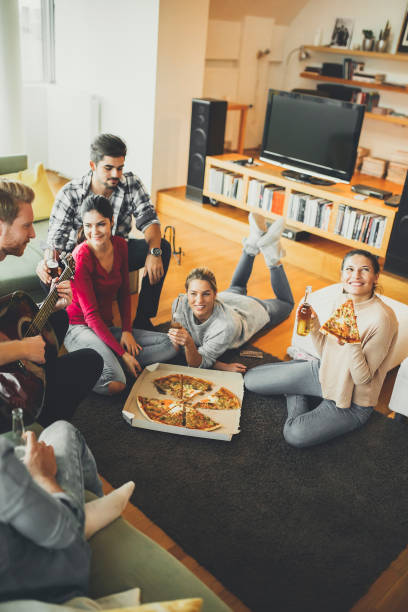istock Young people eating pizza and drinking cider in the room 831050178