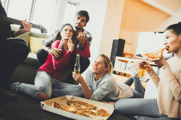 istock Young people eating pizza and drinking cider in the room 831050358
