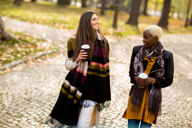 istock Two young pretty multiracial girlfriends at autumn day 831052648