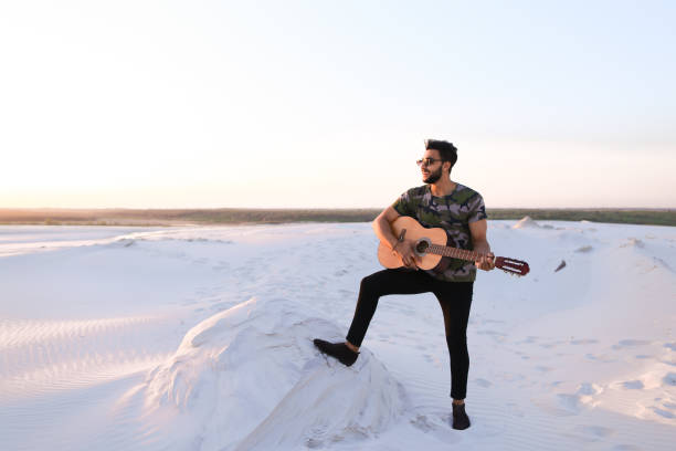 beau mec arabe jouant de la guitare, debout sur la colline entre sable - musical instrument nature outdoors musician photos et images de collection