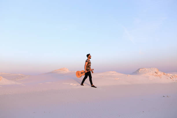 majestueux jeune homme musulman se promène avec guitare en mains par l’intermédiaire de dese - musical instrument nature outdoors musician photos et images de collection