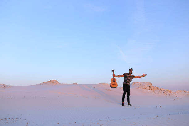 mec arab va inspiré par la beauté du désert et joue la guitare stri - musical instrument nature outdoors musician photos et images de collection