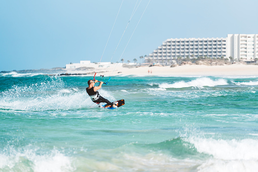 Young athlete practising kiteboarding, success in sports, taking care of his body, enjoying aquatic sports, summer vacations, young male sportsman, adrenaline sports, kitesurfing on big waves, Fuerteventura, Canary islands