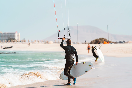 Young athlete practising kiteboarding, success in sports, taking care of his body, enjoying aquatic sports, summer vacations, young male sportsman, adrenaline sports, kitesurfing on big waves, Fuerteventura, Canary islands