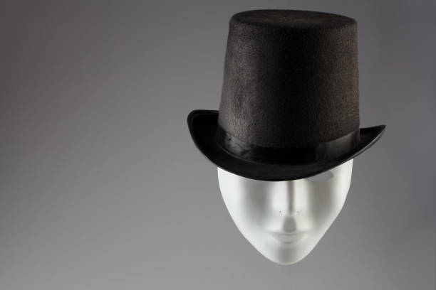 istock White mask wearing black top hat on gray background with copy space 831070682