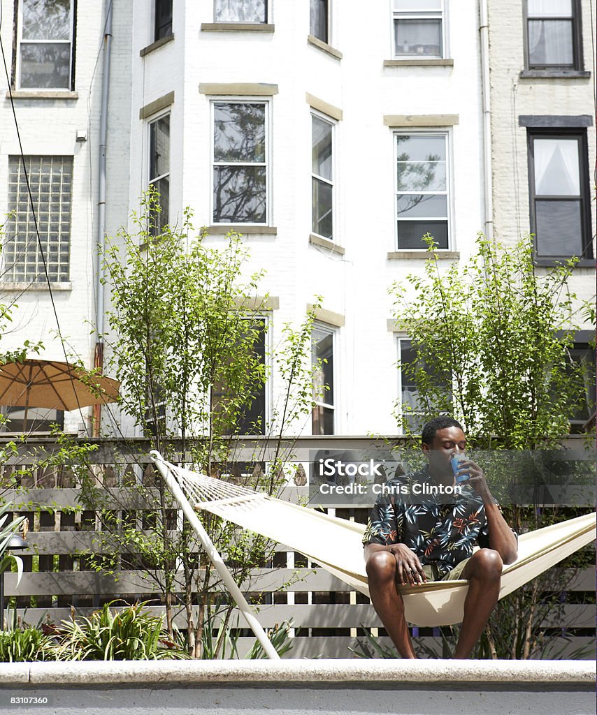 Man relaxing in urban backyard hammock  Fence Stock Photo