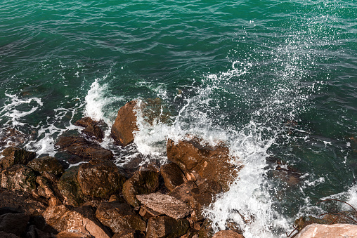 Breaking wave in rocky coastline. Seascape from viewpoint. Splashing droplets close-up. Foz, A Mariña, Lugo province, Galicia, Spain.