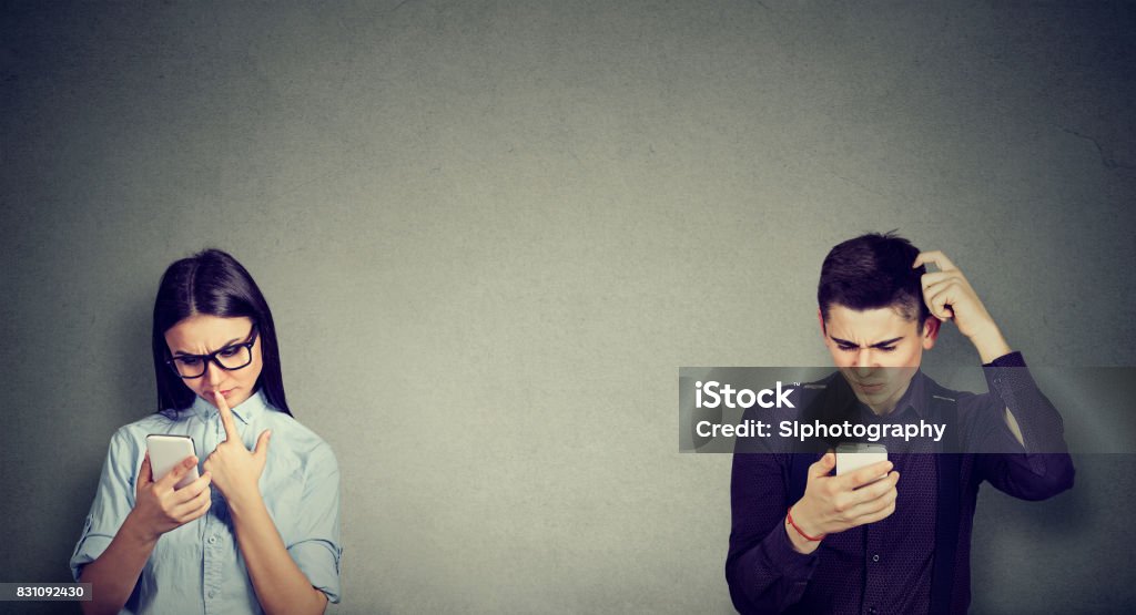 Perplexed young man and woman looking at mobile phone Communication Problems Stock Photo