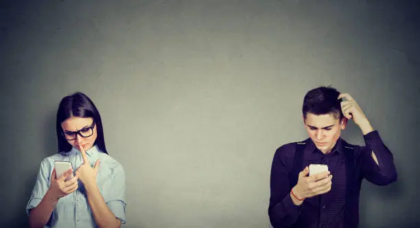 Perplexed young man and woman looking at mobile phone