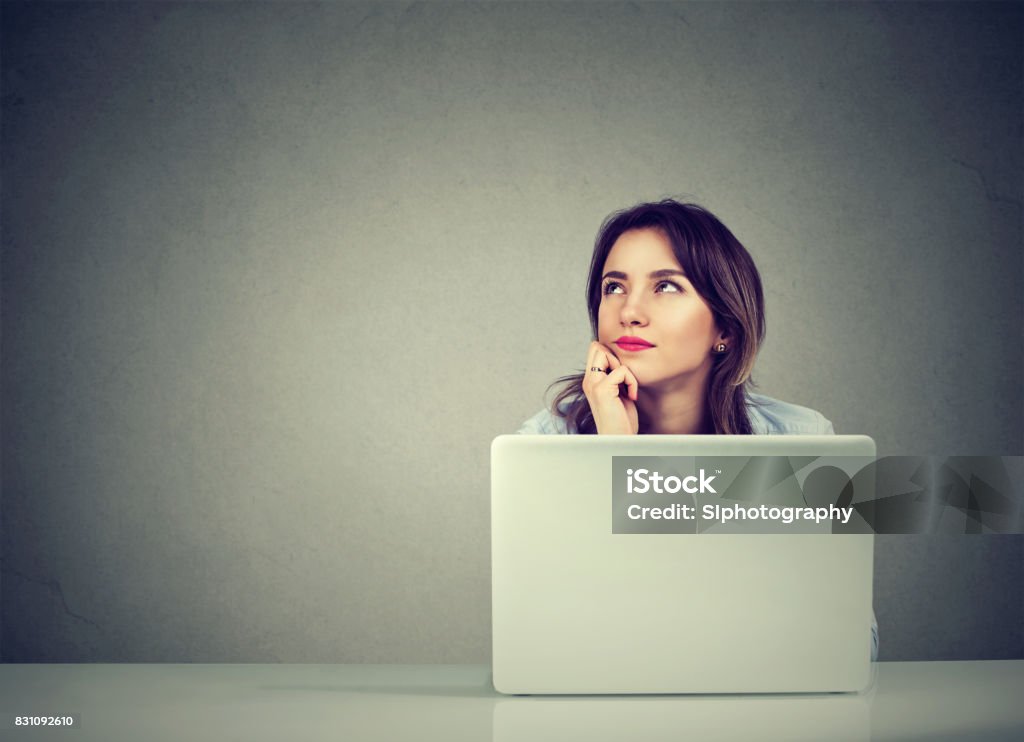 young business woman thinking daydreaming sitting at desk with laptop computer Working Stock Photo