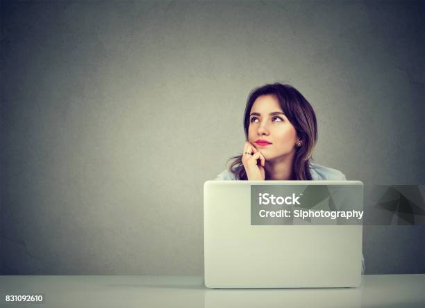 Young Business Woman Thinking Daydreaming Sitting At Desk With Laptop Computer Stock Photo - Download Image Now