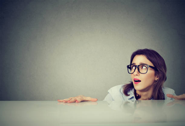 anxious woman hiding peeking from under the table - hiding humor occupation office imagens e fotografias de stock