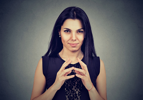 Sly, scheming woman plotting something isolated on gray background. Negative human emotions, feelings, attitude