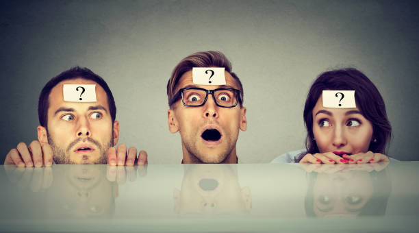 istock Scared young people two men and a woman with question mark hiding peeking from under the table 831093532
