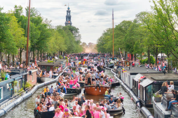 Color image of the famous canal parade during the closing days of Gay Pride in Amsterdam, the Netherlands. Spectators watch and cheer the participant. Various organisations, NGOs, foundations, sport clubs and companies sail with their flamboyant boats in order to greet the spectators along the Prinsengracht in centrum Amsterdam. Canal parade is a very famous event of the year for the LGBT community.