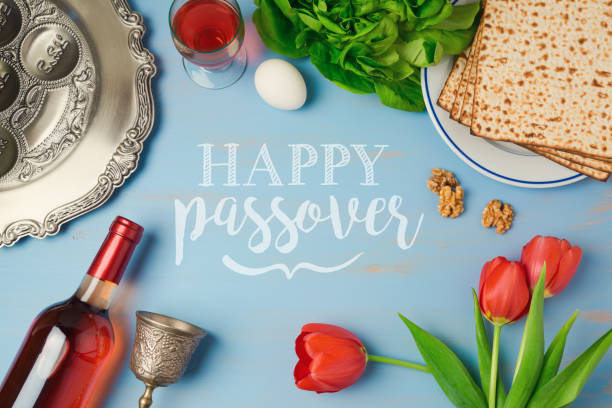 ostern urlaub grusskarte mit seder platte matzoh, tulpen und blumen weinflasche auf hölzernen hintergrund. draufsicht von oben - passover seder seder plate table stock-fotos und bilder