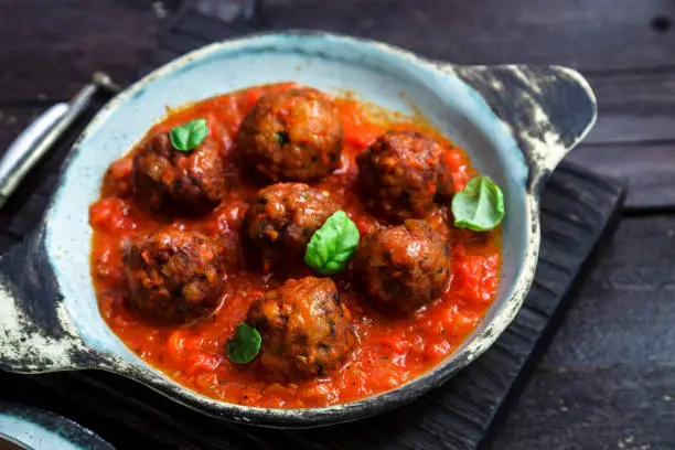 Meatballs with tomato sauce on a ceramic pan. Close view, rustic style.