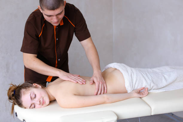 istock Cute male massage therapist does restoring procedure for back of 831149130