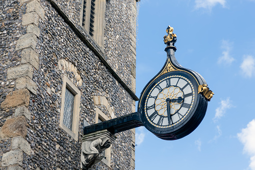 Old wall clock on side ancient tower downtown in Canterbury city, England