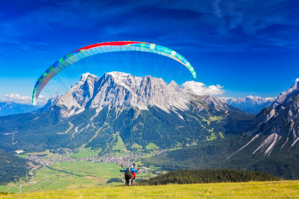 gleitschirmfliegen in den alpen, tandem-gleitschirm starten einen flug, berg zugspitze, alpen - paragliding sport austria parachuting stock-fotos und bilder