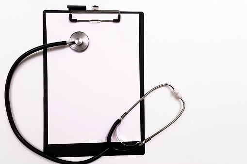 Black clipboard with stethoscope. Medicine concept. Stethoscope and clipboard with blank white sheet of paper and copy space