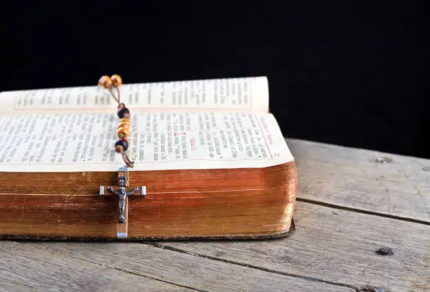 The book of Catholic Church liturgy and rosary beads on the wooden table
