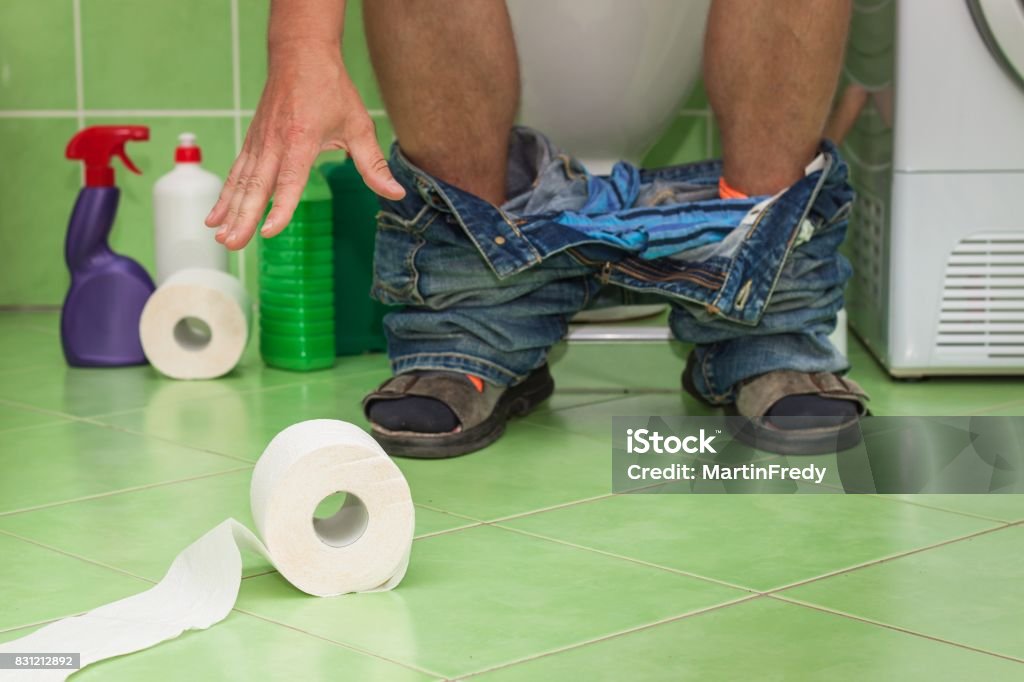 Man sitting on a toilet in a family house. Abdominal pain. Diarrhea. Man sitting on a toilet in a family house. Abdominal pain. Diarrhea Adult Stock Photo