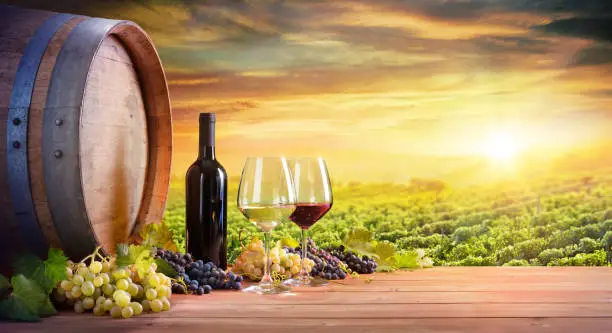 Photo of Wine Glasses And Bottle With Barrel In Vineyard At Sunset
