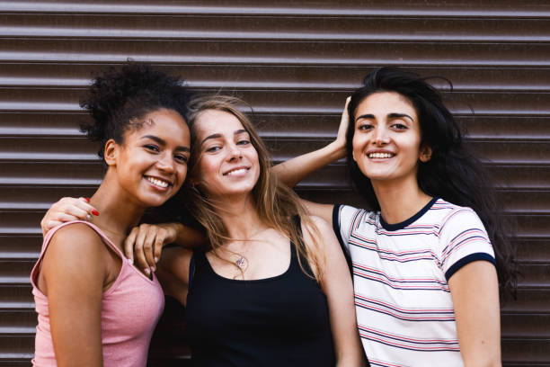 istock Smiling female friends standing together, looking at camera 831216500