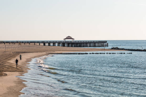People on Buckroe Beach Fishing Pier in Hampton, VA Hampton, Virginia - July 9, 2017:  People on Buckroe Beach in the early morning near the viewing pier with gazebo.  Originally a plantation in 1619, the area is now a public beach and park. hampton virginia photos stock pictures, royalty-free photos & images