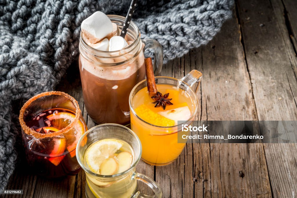 Set of 4 autumn drinks Selection of various autumn traditional drinks: hot chocolate with marshmallow, tea with lemon and ginger, white pumpkin spicy sangria, mulled wine. On wooden rustic table, copy space, selective focus Cocktail Stock Photo