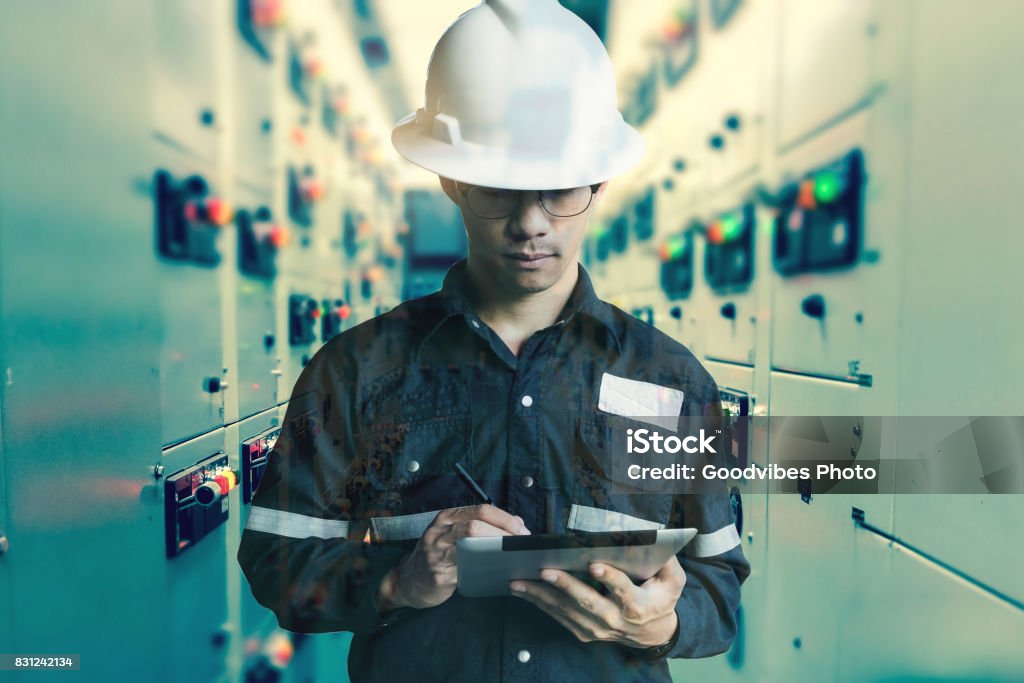 Double exposure of  Engineer or Technician man working with tablet in switch gear electrical room of oil and gas platform or plant industrial for monitor process, business and industry concept. Water Stock Photo