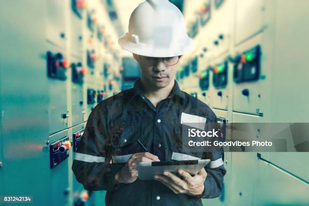 Double Exposure Of Engineer Or Technician Man Working With Tablet In Switch Gear Electrical Room Of Oil And Gas Platform Or Plant Industrial For Monitor Process Business And Industry Concept Stock Photo - Download Image Now