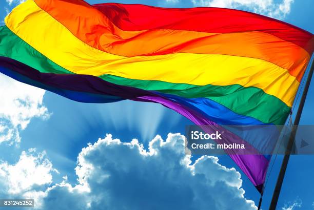 Rainbow Flag On Cloudy Sky Background Stock Photo - Download Image Now - LGBTQIA Pride Event, LGBTQIA Rights, Pride