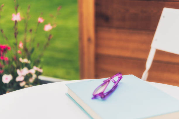 istock Summer reading. Book and eyeglasses in outdoor setting 831249744